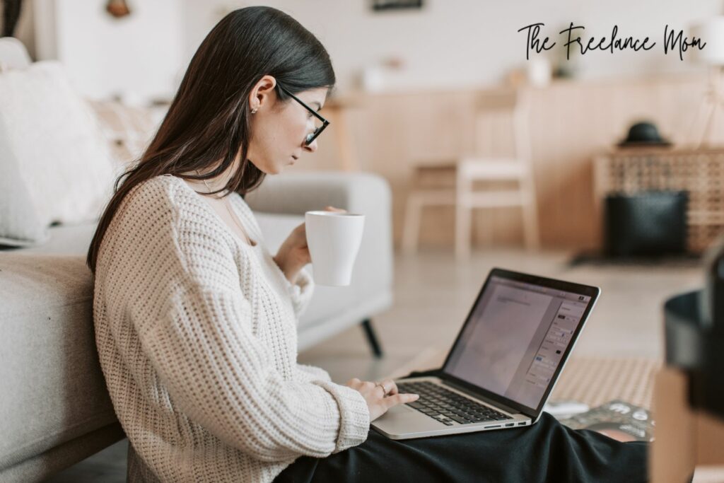 woman writing at a laptop computer with coffee mug